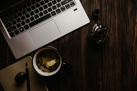 silver laptop beside black ceramic mug on brown wooden table